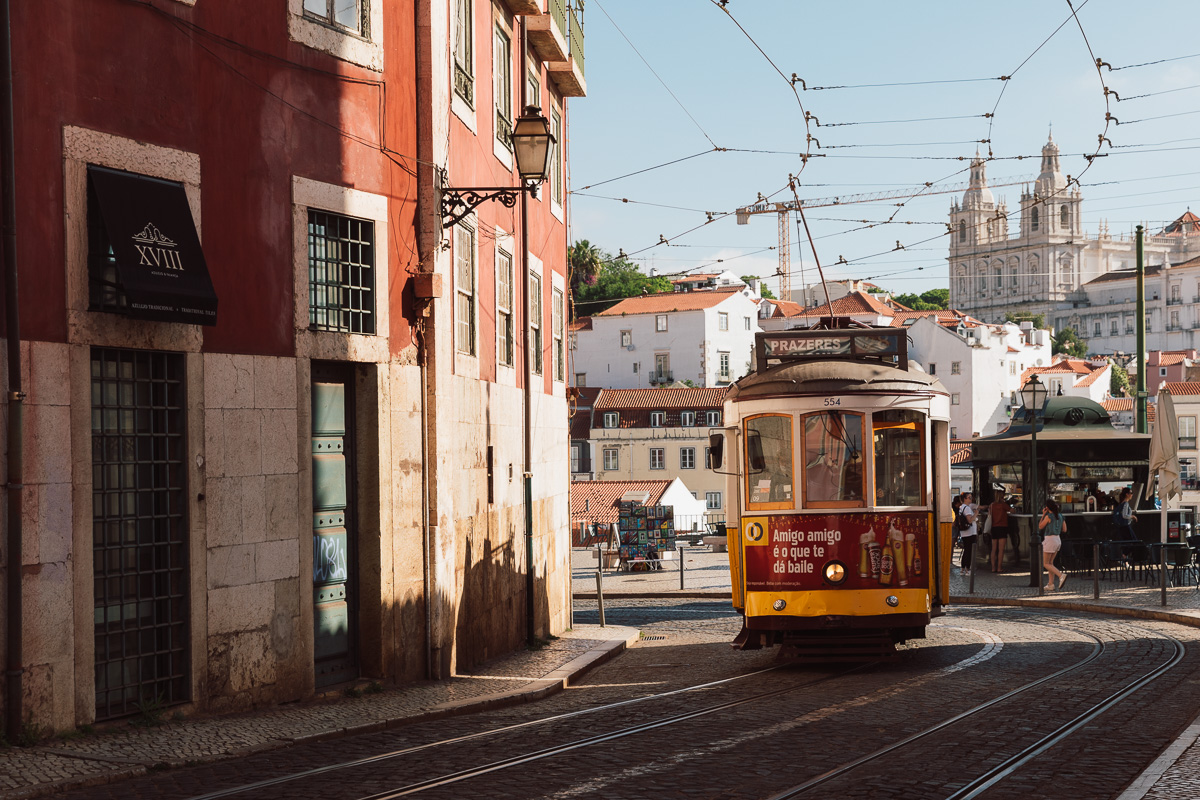 A yellow tram on a sunlit street in Lisbon