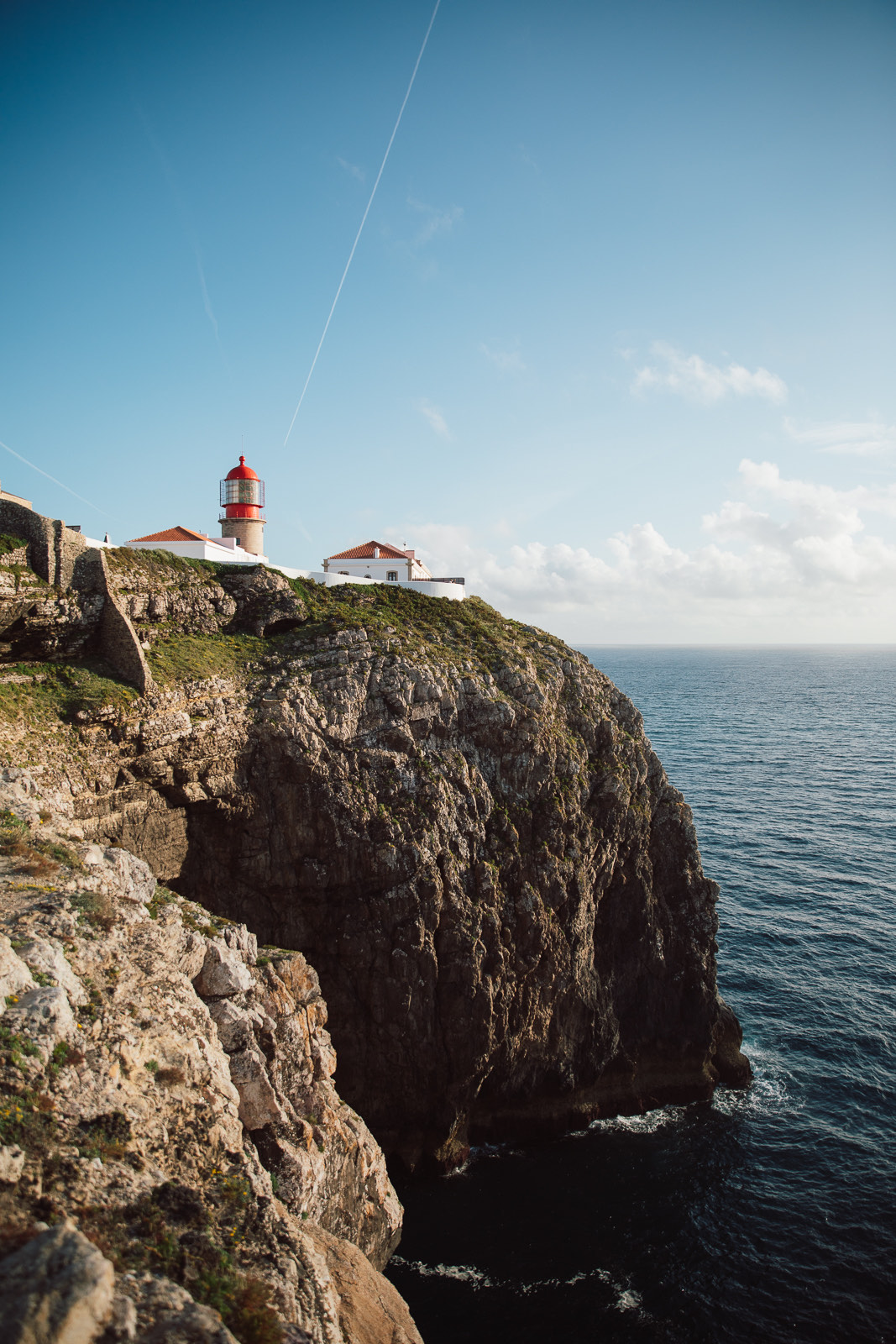 A red-domed lighthouse on the sea cliffs at Cape St. Vincent near Sagres