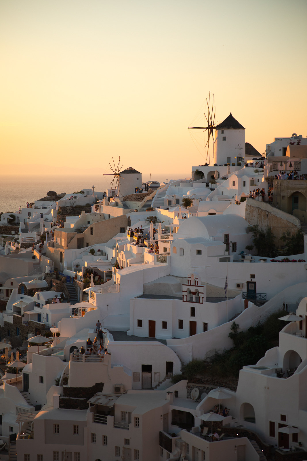 Whitewashed houses and windmills above the sea at sunset in Oia, Santorini